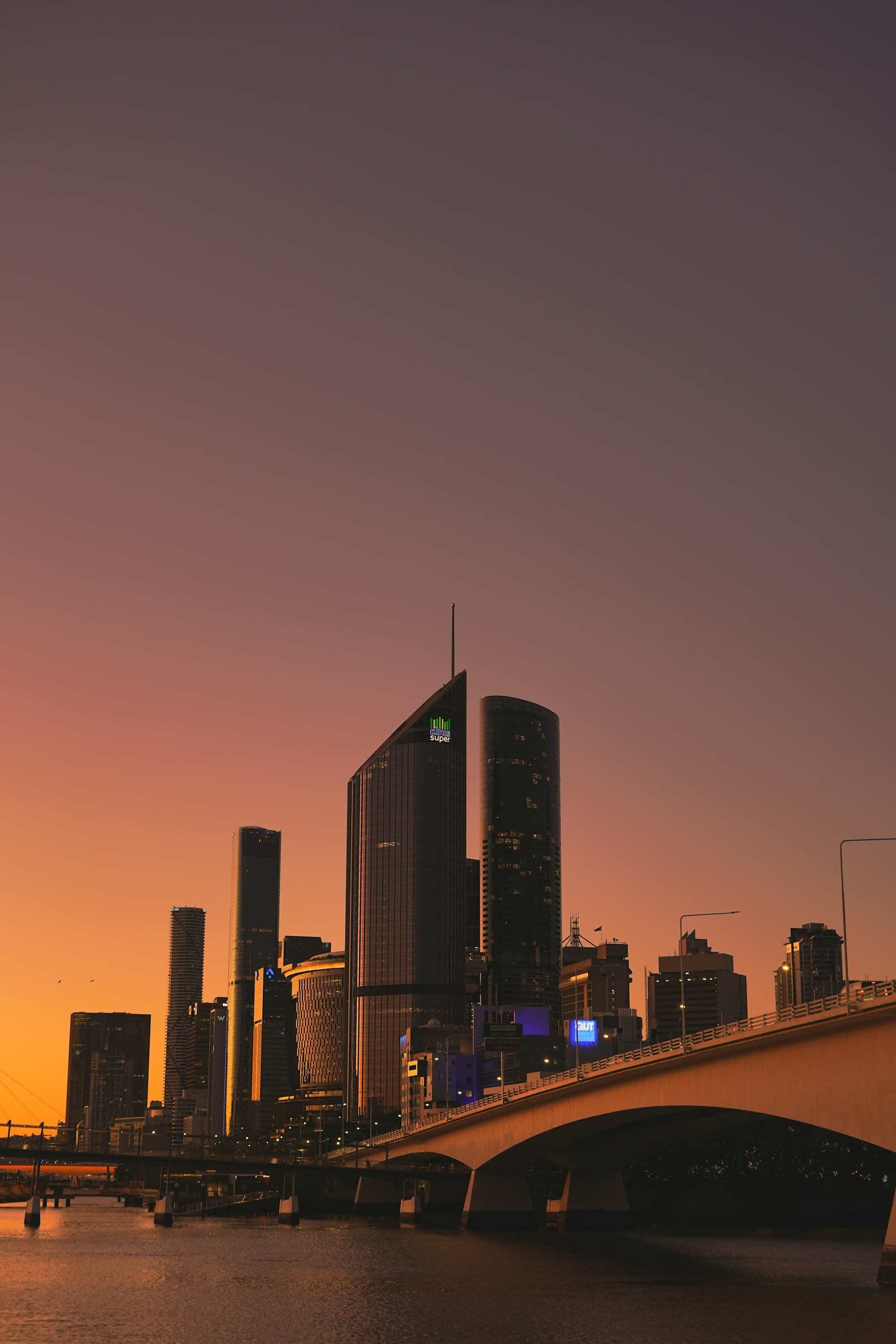 Brisbane's skyline and a bridge at sunset.