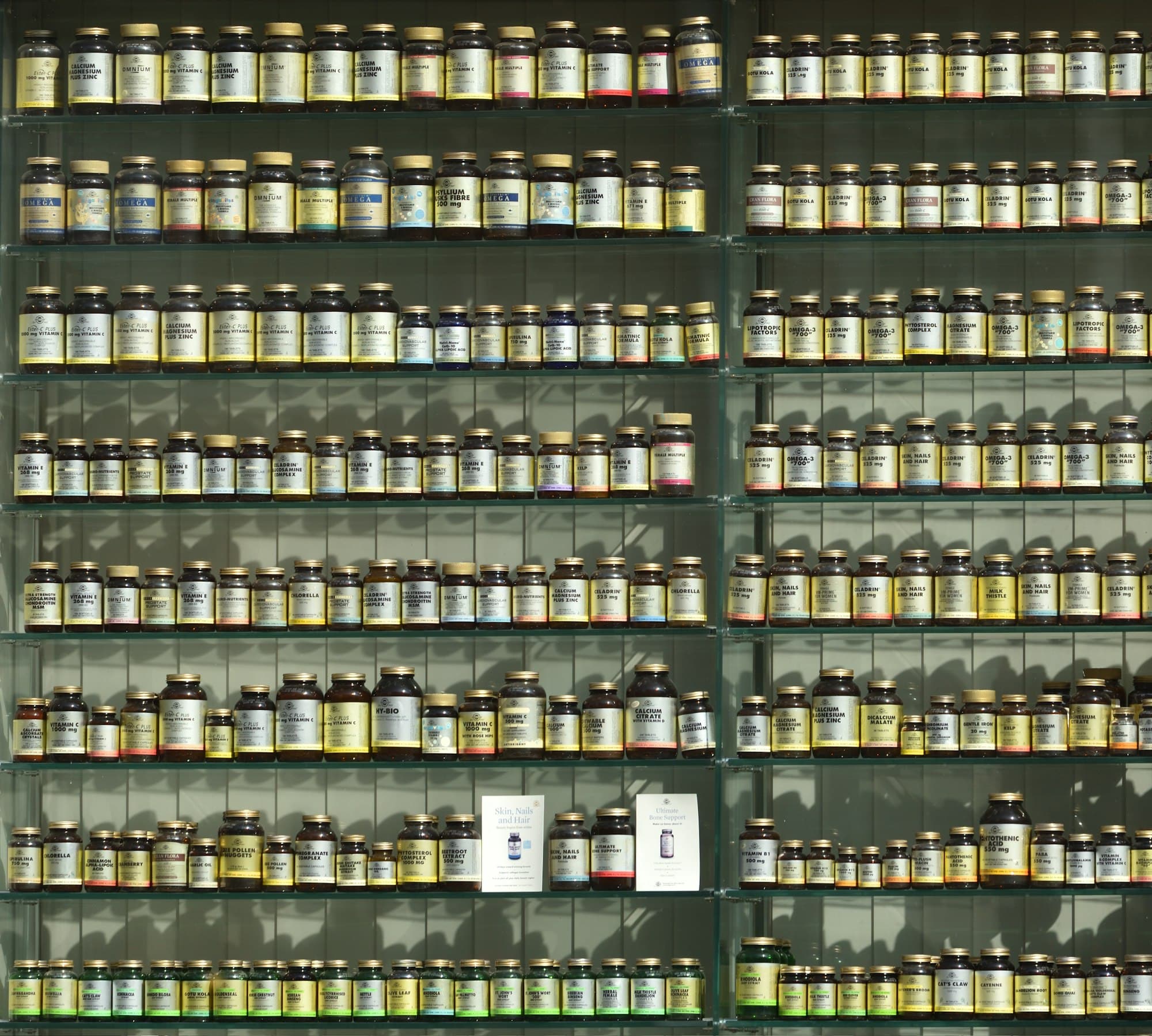 Rows of labelled medicine bottles on pharmacy shelves.