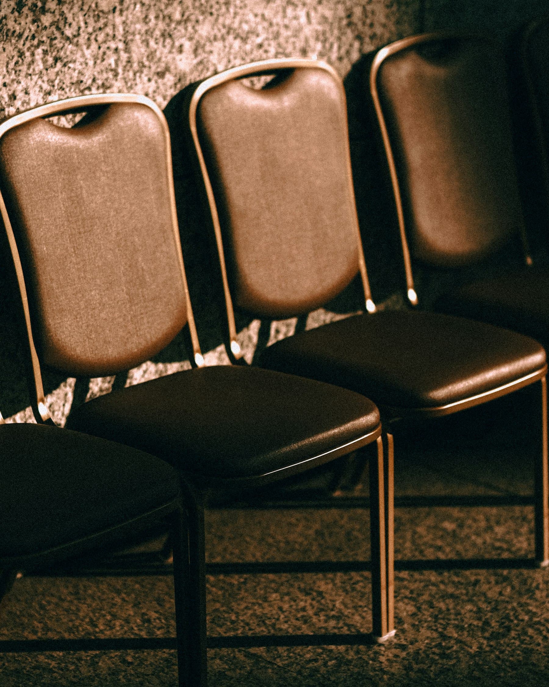 A row of empty leather chairs against a wall.