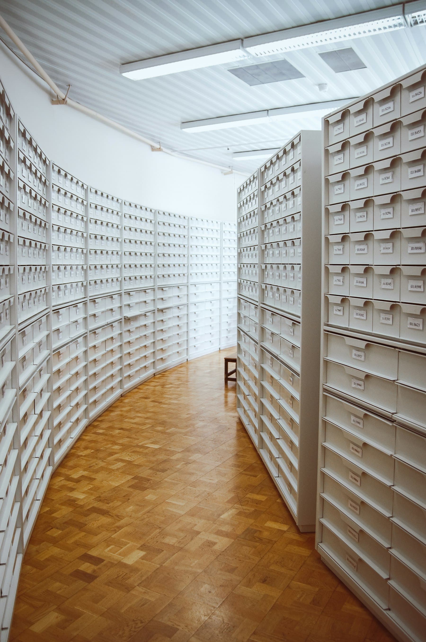 A long aisle between walls of white pharmacy drawers.