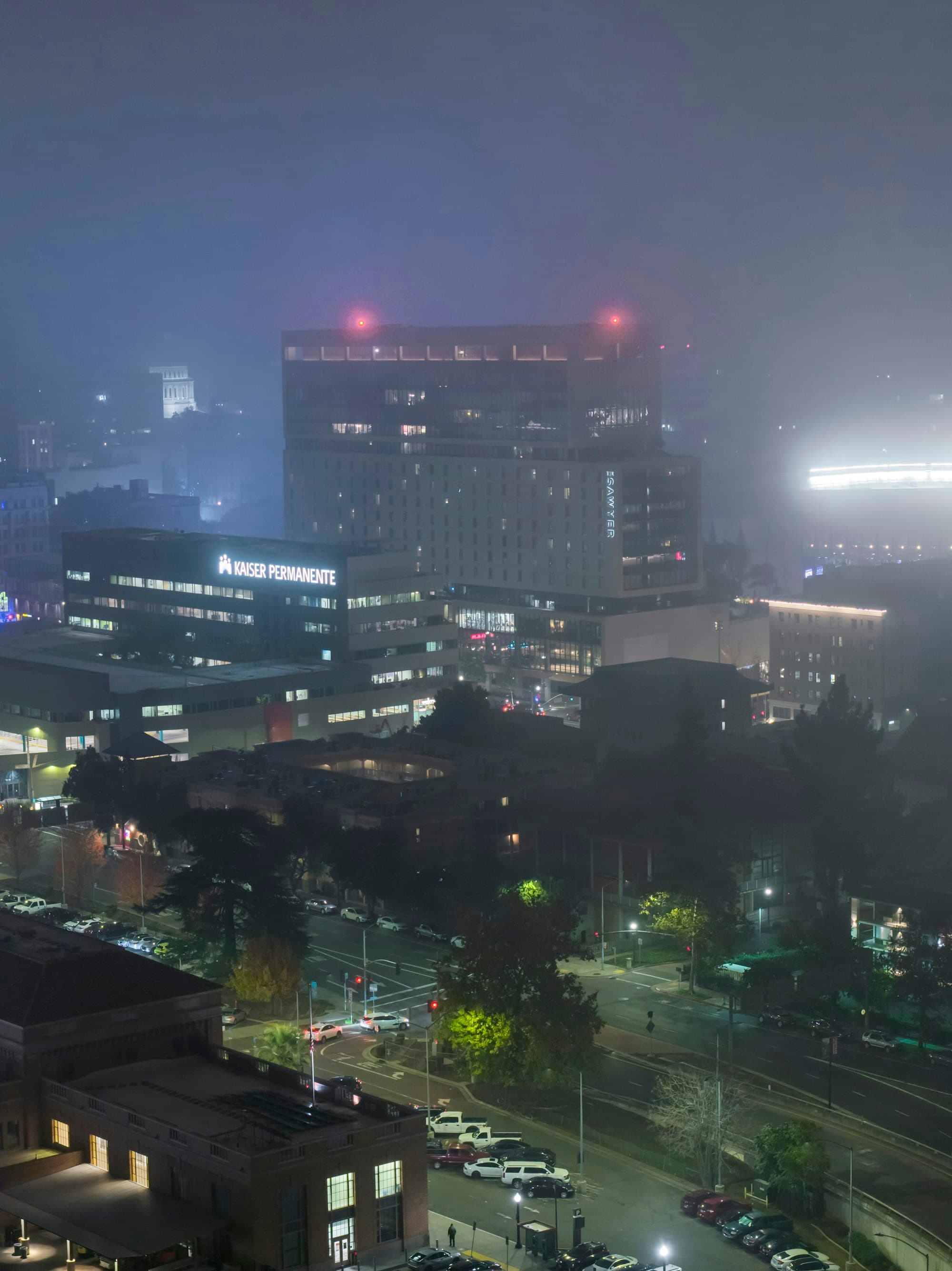 A city skyline at night, half lost in fog.